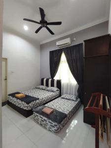 two beds in a room with a ceiling fan at Awang's Villa Homestay in Kampong Gong Badak