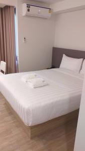 Una cama blanca con dos toallas encima. en Prom Hotel, en Bangkok