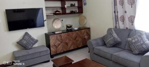 ein Wohnzimmer mit 2 Sofas und einem Flachbild-TV in der Unterkunft Luxurious 3 bedroom Furnished Apartment R1 in Shanzu