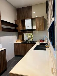a kitchen with wooden cabinets and a white counter top at Bunga Raya Villa By Malvacae Homestays Shah Alam in Shah Alam