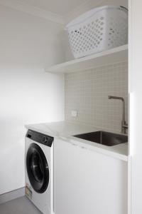uma cozinha com uma máquina de lavar roupa e um lavatório em The Corner on Te Mata em Havelock North