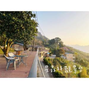 eine Holzterrasse mit einem Tisch und Stühlen darauf in der Unterkunft 星森林包棟住宿-台中東勢-山區景觀 in Dongshi