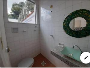 a bathroom with a toilet and a mirror and a window at Casaclassea in Juiz de Fora
