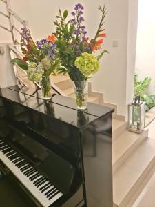 two vases with flowers sitting on top of a piano at Lotus Colombo Guesthouse in Colombo