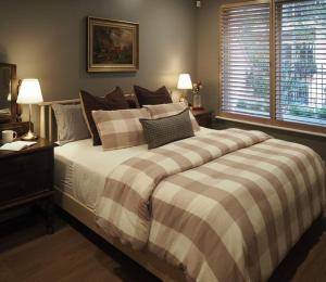 1 dormitorio con 1 cama grande con manta a rayas en Charlie on Charlick - Fully Renovated 1BR Apt en Adelaida