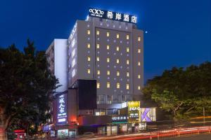 um edifício com um sinal em cima dele à noite em Xana Hotelle - Guangzhou Jiangnanxi Metro Station em Guangzhou