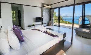 a bedroom with a white bed with a view of the ocean at Villa Moonshadow - Multiple Award Winning Villa in Chaweng Noi Beach