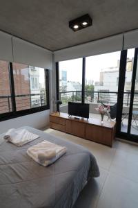 OWN Belgrano Studios & Suites في بوينس آيرس: غرفة نوم بسرير ومكتب ونوافذ