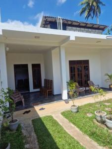 una casa bianca con palme in un cortile di Private AC BEDROOM in 2 Bed Villa - Coconut Beach a Midigama East