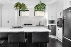 een keuken met een wit aanrecht en zwarte apparaten bij Entire Home with Views and Heated Pool in Newcastle