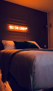 1 cama en un dormitorio con un cartel en la pared en 150 de Grey Studio pour 2 avec SPA, Vue sur mer, en La Trinité