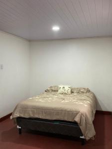 Cama en habitación con pared blanca en CasaZheng, en San José