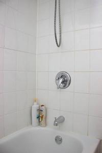 a white tiled bathroom with a tub and a shower at Studio & Office -Walk anywhere Downtown + Hospital in Montréal