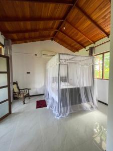 Schlafzimmer mit einem Bett mit Moskitonetz in der Unterkunft Dinuri villa in Tangalle