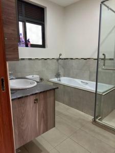 een badkamer met een wastafel, een bad en een douche bij Heavenly Getaways, Nalya in Kampala