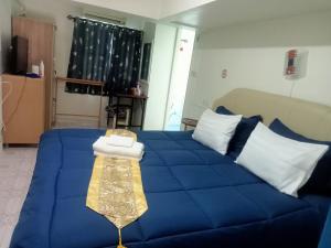 Cama azul con almohadas blancas y manta en Happy Home Guest House en Ban Phe