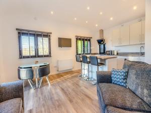 a living room with a couch and a kitchen at Kestrel Lodge in Little Witley