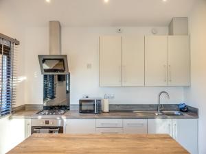 a kitchen with white cabinets and a sink and a microwave at Kestrel Lodge in Little Witley