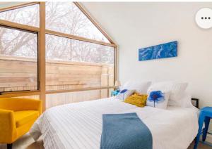 a bedroom with a large bed and a yellow chair at Tiny House Haven in Peterborough