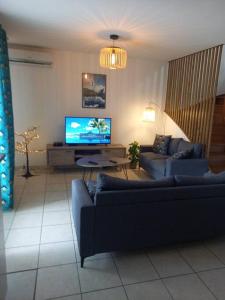 uma sala de estar com 2 sofás e uma televisão de ecrã plano em Appartement la marine em Saint-Leu