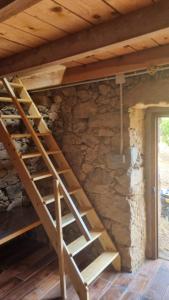 a wooden staircase in a room with a stone wall at Langhjuledda in Grosseto-Prugna