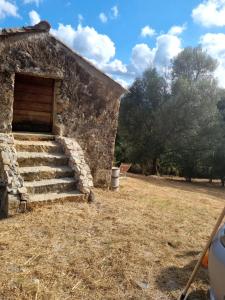 een stenen gebouw met een deur en een trap in een veld bij Langhjuledda in Grosseto-Prugna