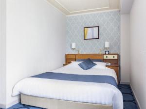 a bedroom with a large white bed and a mirror at Senri Hankyu Hotel Osaka in Toyonaka