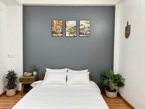 a bedroom with a white bed with three paintings on the wall at The little Ha Noi in Hanoi