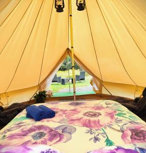 a yellow tent with a bed with flowers on it at Glamping at Zeehan Bush Camp in Zeehan