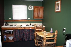 cocina con paredes verdes, fregadero y mesa en Timber Creek Chalets- 4 chalet en Estes Park