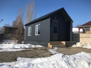 a black house with snow in front of it at Cottage town D&N in Karakol