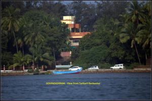 dos coches y un barco azul en un cuerpo de agua en Govindaashram-Tarkarli en Bhogwe