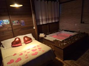 a bedroom with a bed and a tub with hearts at pimenta rosa guesthouse in Praia do Rosa