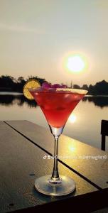 a drink sitting on a table with the sunset in the background at Baantia Chomtawan in Surat Thani