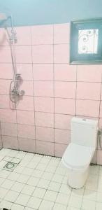 baño con aseo y pared de azulejos rosas en Appartement meublé, en Douala