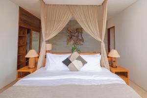 1 dormitorio con 1 cama blanca con cortinas y 2 lámparas en Villa Kaliente, en Nusa Penida