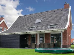 uma casa com um telhado de gambrel e um trampolim em Vacation home with sauna in Zeeland em Colijnsplaat