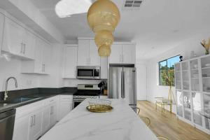 a kitchen with white cabinets and a table with a bowl on it at Mesmerizing Villa. Perfect for group retreats in Los Angeles