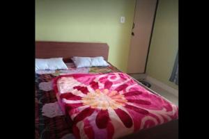 a bedroom with a bed with a pink and white comforter at Vivek Palace by StayApart in Barkot