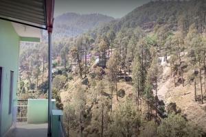 a room with a view of a mountain with trees at Vivek Palace by StayApart in Barkot