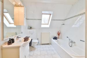 a bathroom with a tub and a toilet and a sink at Boddenhuus - Traumhaus mit Steg und Boot in Zudar +29 photos