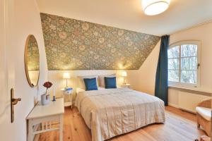 a bedroom with a large bed with blue pillows at Boddenhuus - Traumhaus mit Steg und Boot in Zudar