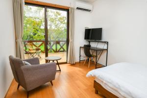 ein Schlafzimmer mit einem Bett und einem Stuhl sowie einem Balkon in der Unterkunft Hotel Circle one in Hitoyoshi