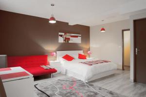 a bedroom with a white bed and a red couch at Studios du Marché au Bois in Périgueux