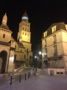 un groupe de bâtiments avec une tour d'horloge la nuit dans l'établissement Studios du Marché au Bois, à Périgueux