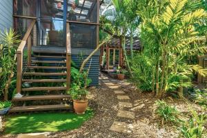 Enchanted Garden Cottage with Bikes في Russell Island: منزل امامه درج والنخيل