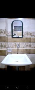 lavabo blanco en el baño con espejo en New hotel blue stars, en Varanasi