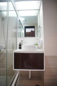 a bathroom with a sink and a shower with a mirror at Simple Ortigas Suite w/ City View, & Pool 3017 in Manila