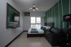 een slaapkamer met een bed, een bank en een televisie bij Simple Ortigas Suite w/ City View, & Pool 3017 in Manilla
