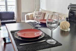 - une table avec deux assiettes et des verres à vin dans l'établissement Charming apartment in Courbevoie - Welkeys, à Courbevoie